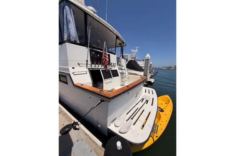 Slide: The Image of 1990 Californian 48 Motor Yacht docked with kayak, American flag, and fishing rods. - 7