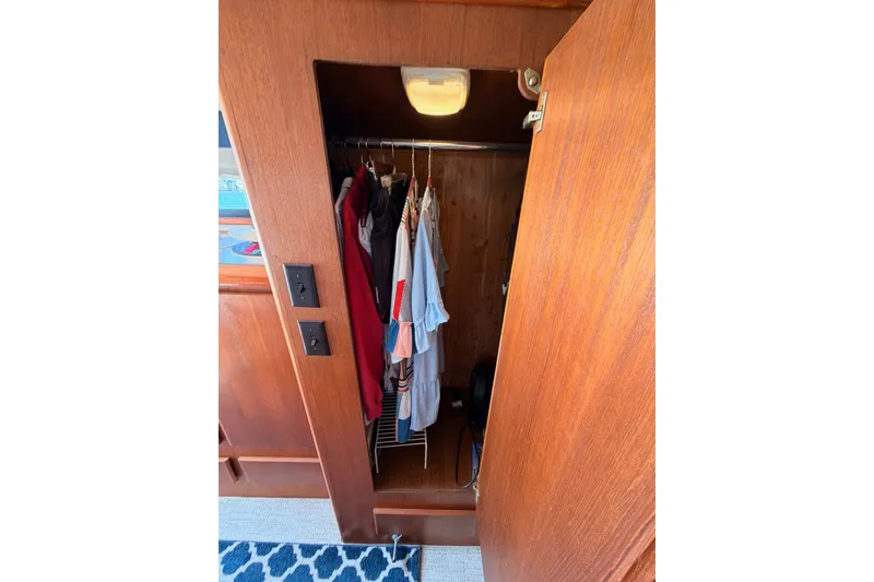Slide: The Image of Wooden closet interior on 1990 Californian 48 Motor Yacht, featuring hanging clothes and a light. - 97