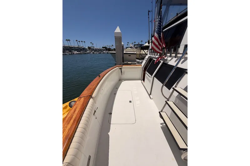Slide: The Image of 1990 Californian 48 Motor Yacht docked, featuring spacious deck and American flag. - 12