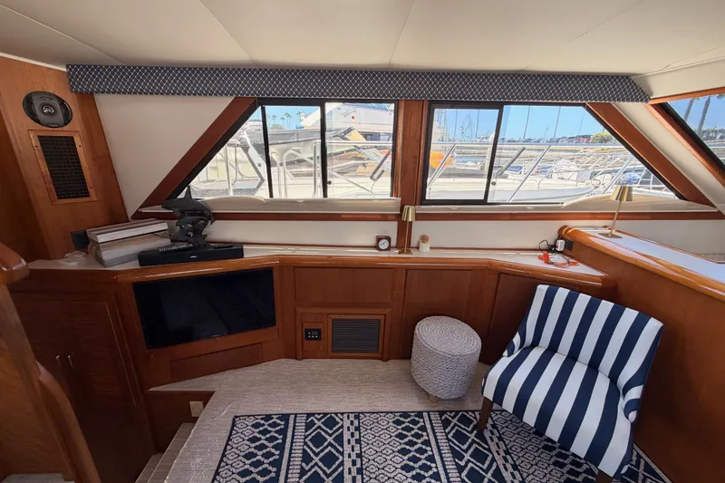 Slide: The Image of Interior of 1990 Californian 48 Motor Yacht with striped chair and large windows. - 60
