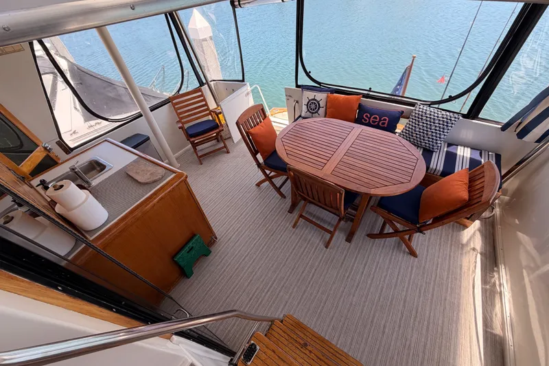Slide: The Image of 1990 Californian 48 Motor Yacht interior with dining area, wooden table, chairs, and nautical decor. - 52