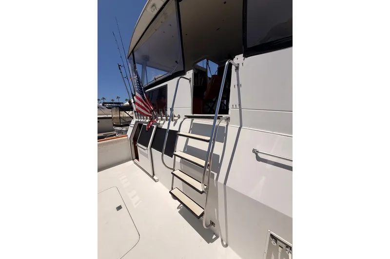 Slide: The Image of 1990 Californian 48 Motor Yacht with American flag and fishing rods on deck. - 11