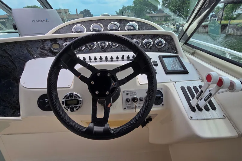 Slide: The Image of Steering wheel and controls of a 2000 Wellcraft 45 Excalibur boat cockpit. - 14