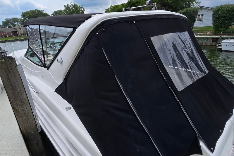 Slide: The Image of 2000 Wellcraft 45 Excalibur boat docked, featuring black canvas cover and sleek white hull. - 4