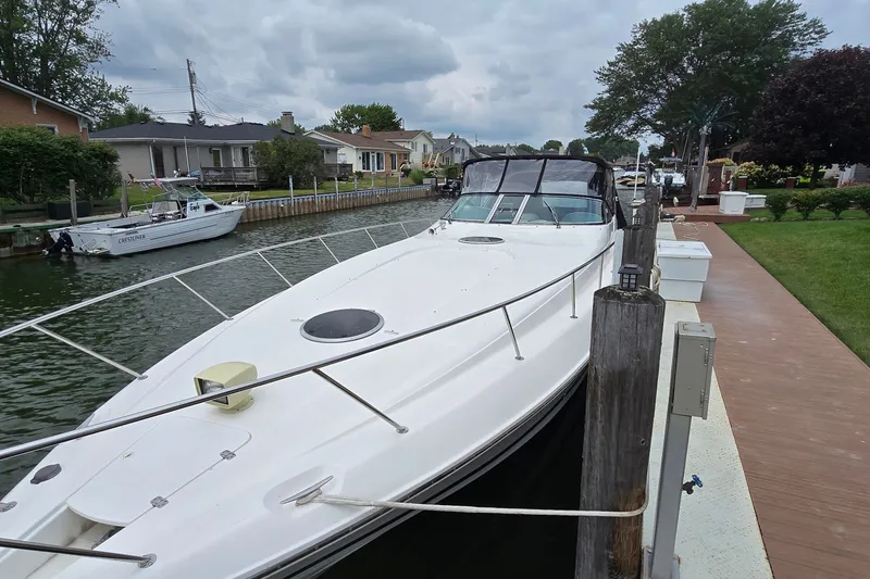 Slide: The Image of 2000 Wellcraft 45 Excalibur docked by a residential canal under cloudy skies. - 2