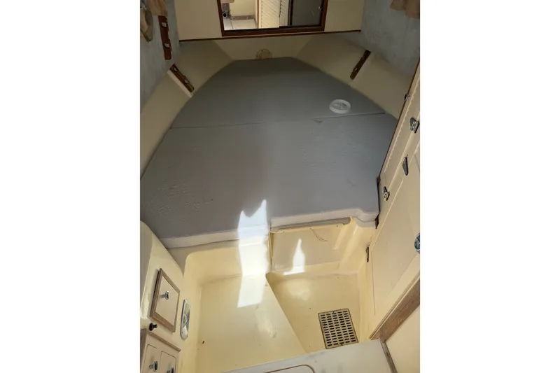 Slide: The Image of Interior cabin of 1992 Mako 260 Walk Around boat, featuring a compact sleeping area. - 14
