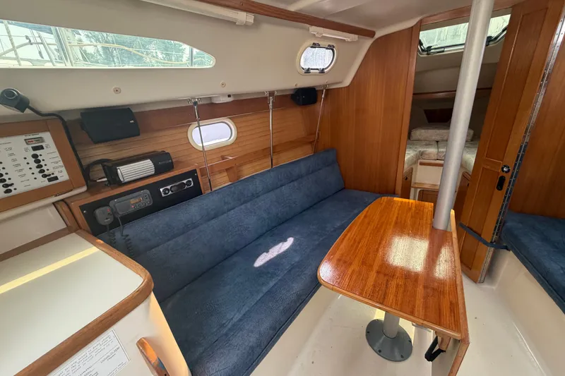 Slide: The Image of Interior of 2003 Catalina 28 MkII sailboat with blue seating and wooden table. - 16
