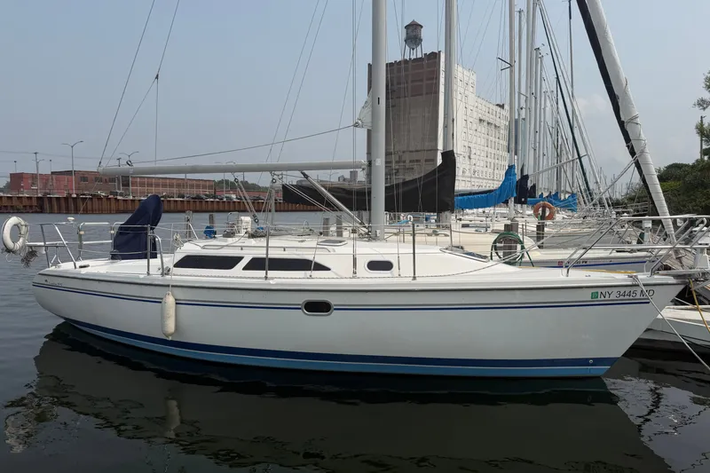 Slide: The Image of 2003 Catalina 28 MkII sailboat docked in a marina, with industrial backdrop. - 1