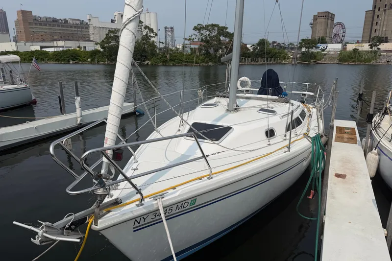 Slide: The Image of 2003 Catalina 28 MkII sailboat docked in a marina, surrounded by industrial buildings. - 3