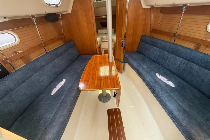 Slide: The Image of Interior of 2003 Catalina 28 MkII sailboat with blue seating and wooden table. - 14