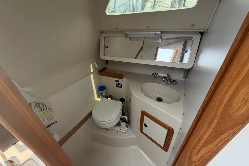 Slide: The Image of Compact bathroom in a 2003 Catalina 28 MkII sailboat, featuring a toilet, sink, and mirror. - 19
