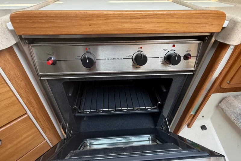 Slide: The Image of Catalina 28 MkII 2003 yacht kitchen oven with stainless steel controls and wooden cabinetry. - 24