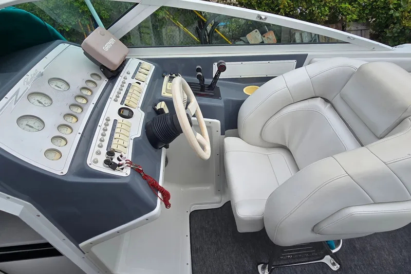 Slide: The Image of Cockpit of a 1995 Powerquest 290 Enticer boat with white seating and control panel. - 13