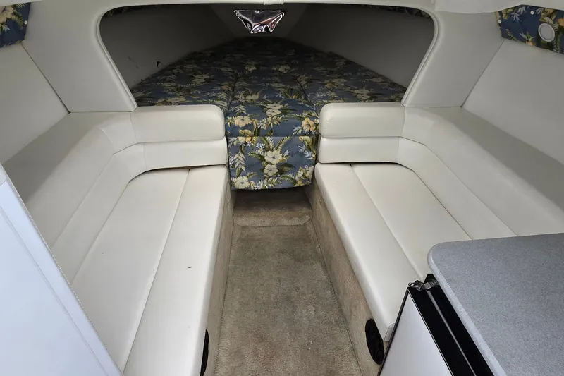 Slide: The Image of Interior of 1995 Powerquest 290 Enticer boat with white seating and floral-patterned bedding. - 17