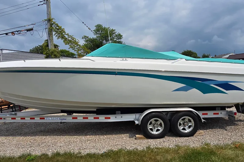 The Image of 1995 Powerquest 290 Enticer boat on trailer with teal cover and blue accents. - 1