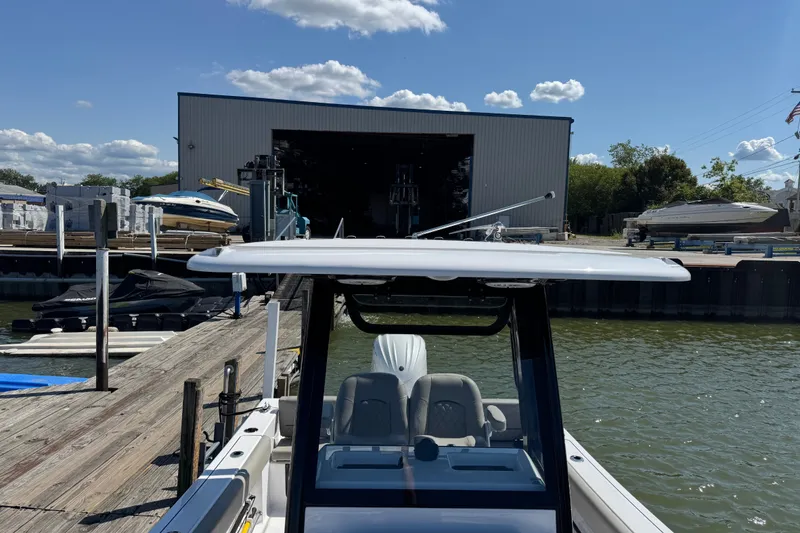 Slide: The Image of 2024 Sportsman Heritage 231 Center Console docked near a boatyard under a clear sky. - 22