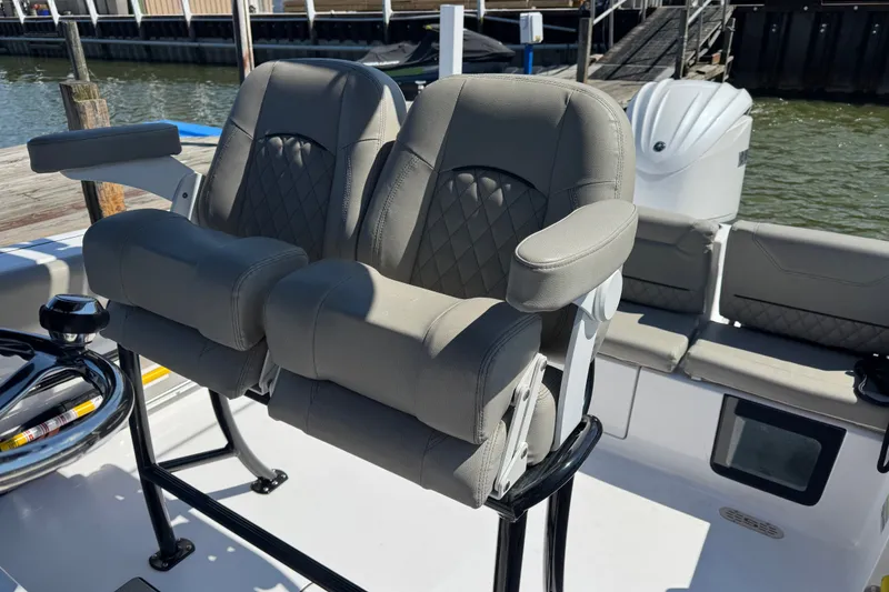 Slide: The Image of 2024 Sportsman Heritage 231 Center Console boat seats with armrests, docked by the water. - 9