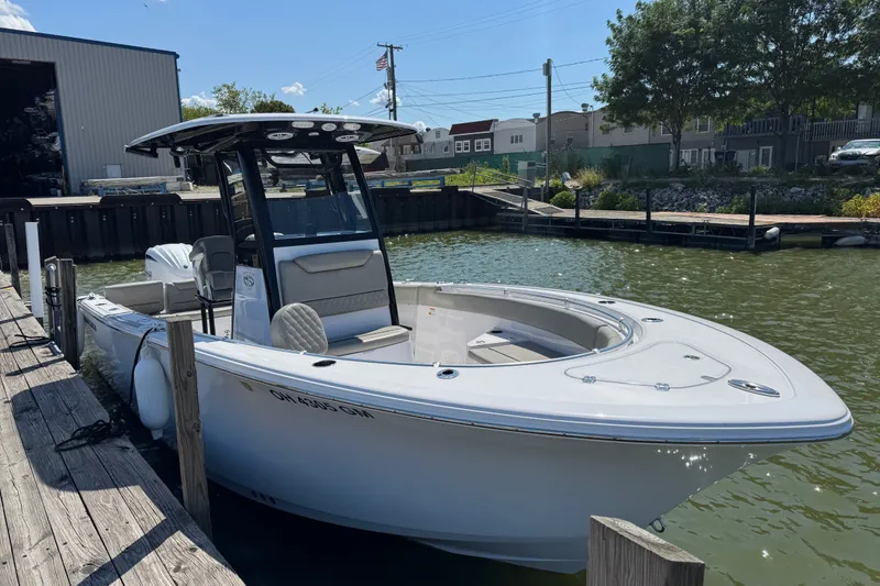 Slide: The Image of 2024 Sportsman Heritage 231 Center Console boat docked in a marina under clear skies. - 1