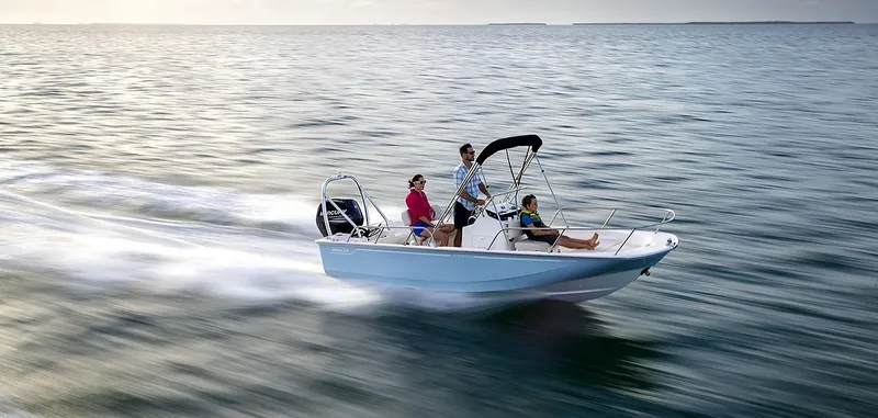 The Image of A 2027 Boston Whaler 170 Montauk speeds across the water with three people on board. - 1
