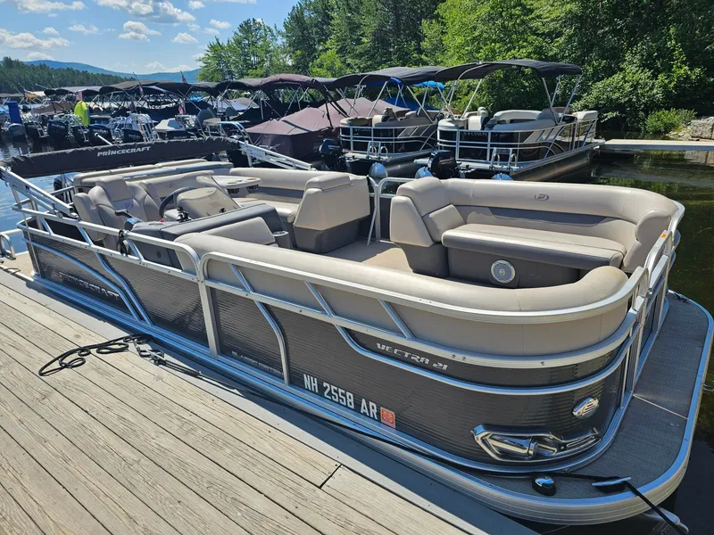 Slide: The Image of A 2019 Princecraft Vectra 21 pontoon boat docked at a wooden pier. It features beige upholstery. - 2