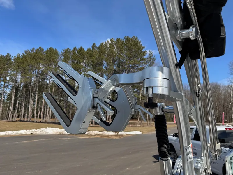 Slide: The Image of Close-up of a silver wakeboard rack on a MasterCraft X10 boat, surrounded by trees. - 30