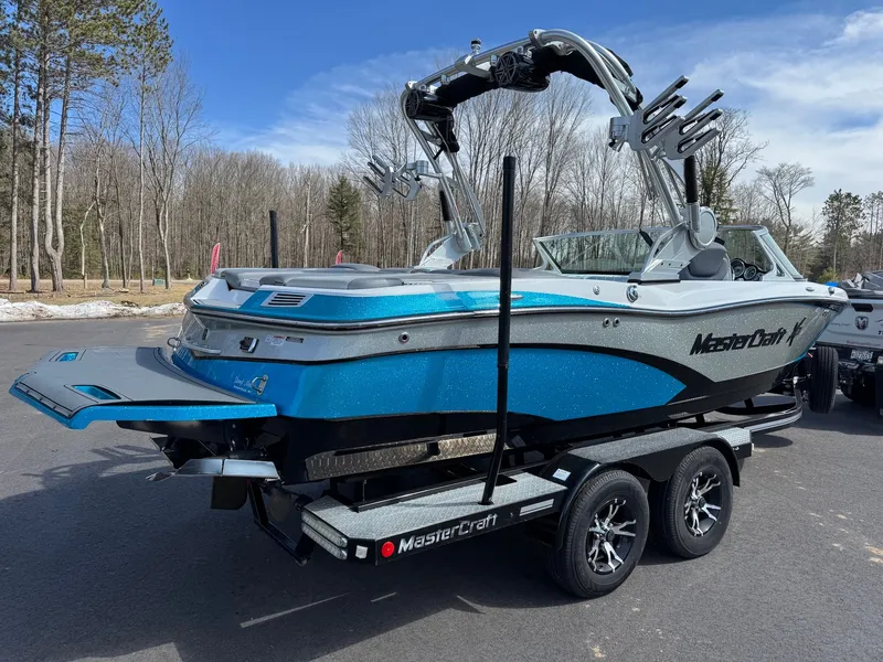 Slide: The Image of A blue 2016 MasterCraft X10 boat on a trailer in a wooded area. - 9