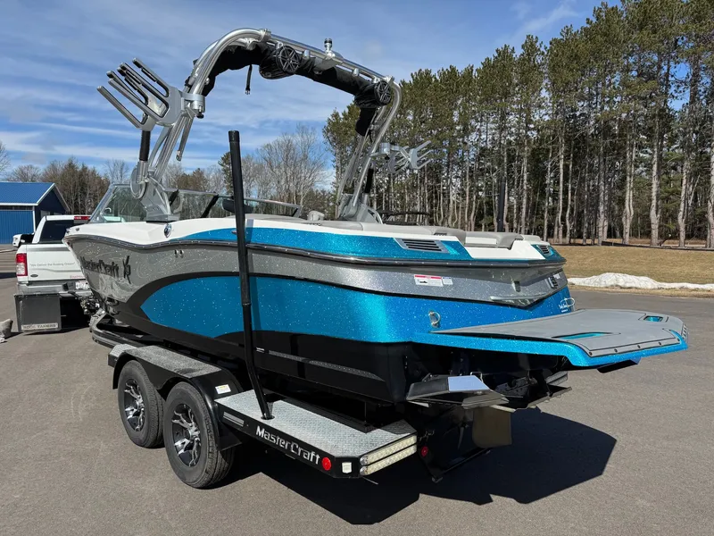 Slide: The Image of A blue and white 2016 MasterCraft X10 on a trailer, surrounded by trees. - 8