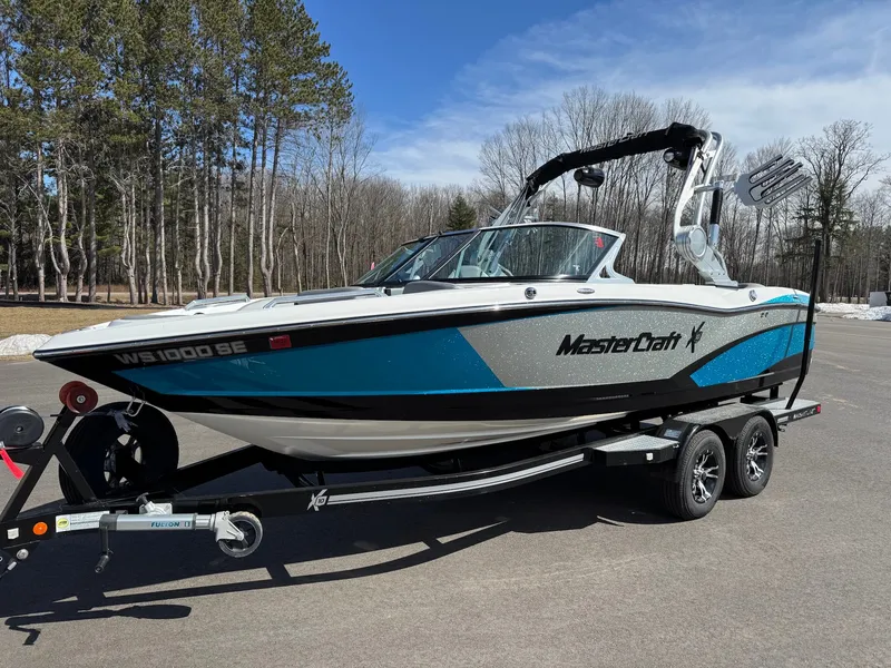 Slide: The Image of A 2016 MasterCraft X10 boat on a trailer, surrounded by trees and a clear sky. - 6