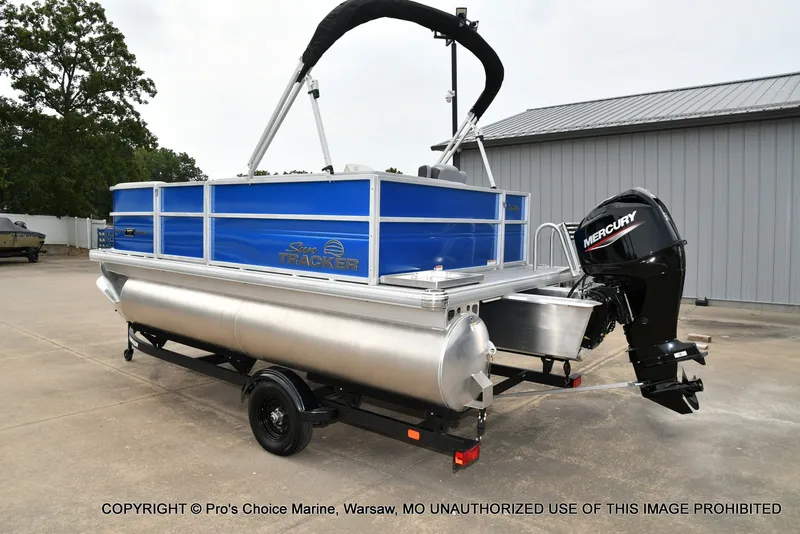 Slide: The Image of A 2027 Sun Tracker Party Barge 16 pontoon boat on a trailer in a yard. - 17