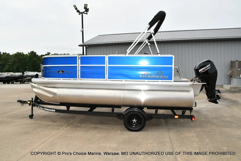Slide: The Image of A 2027 Sun Tracker Party Barge 16 on a trailer in front of a building. - 18