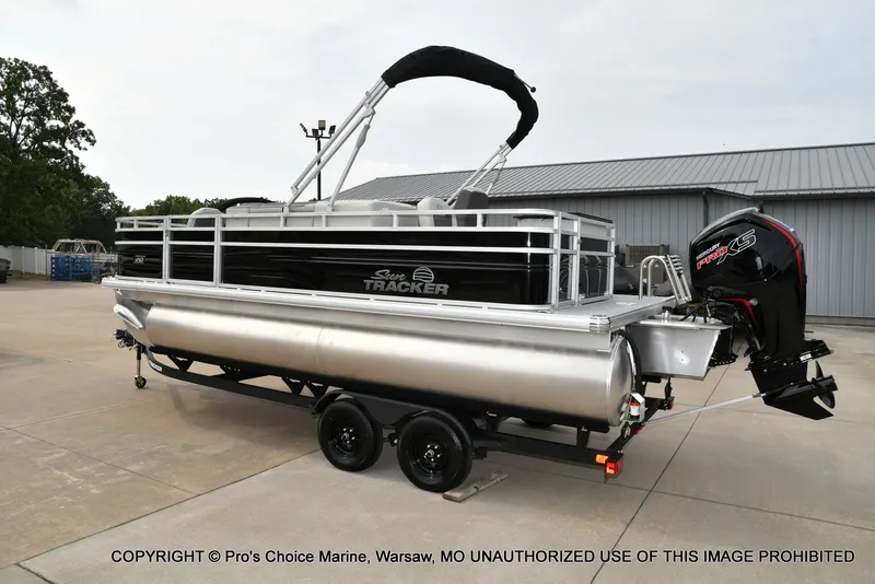 Slide: The Image of A 2027 Sun Tracker Fishin' Barge 20 DLX pontoon boat on a trailer in a yard. - 20