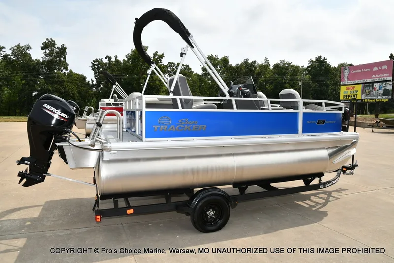 Slide: The Image of A Sun Tracker Bass Buggy 16 XL Select pontoon boat on a trailer, featuring a blue hull and outboard motor. - 18