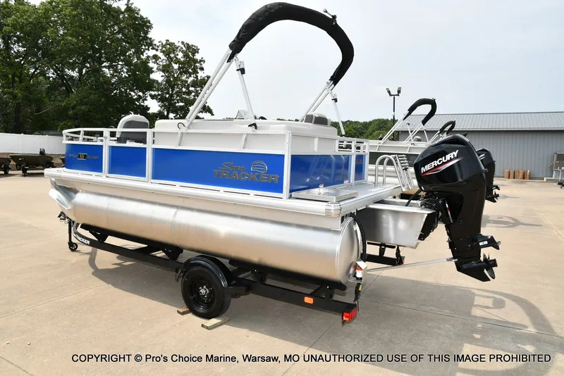 Slide: The Image of A Sun Tracker Bass Buggy 16 XL Select pontoon boat on a trailer, featuring a Mercury outboard motor. - 20