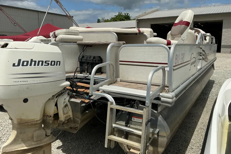 Slide: The Image of 2003 Lowe Trinidad 220 pontoon boat with Johnson outboard motor, parked outdoors. - 4