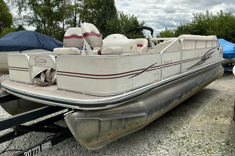 The Image of 2003 Lowe Trinidad 220 pontoon boat on trailer, parked outdoors. - 1