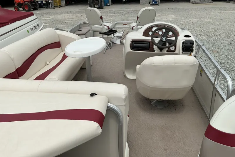 Slide: The Image of 2003 Lowe Trinidad 220 pontoon boat interior with beige and red seating, steering console, and table. - 7