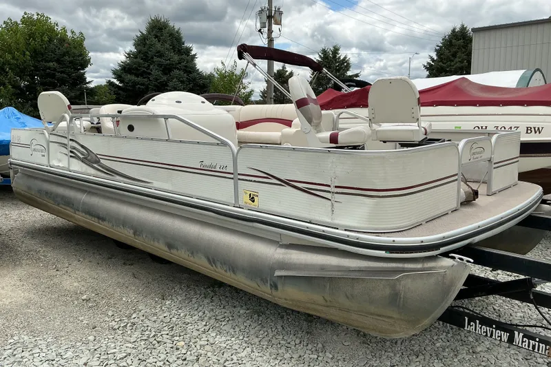 Slide: The Image of 2003 Lowe Trinidad 220 pontoon boat on trailer, parked outdoors under cloudy sky. - 5