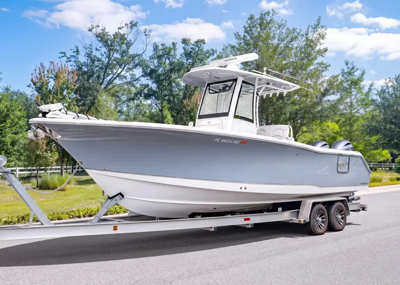 The Image of A 2020 Sea Hunt Gamefish 27CB on a trailer, featuring twin outboard engines and a T-top. - 1
