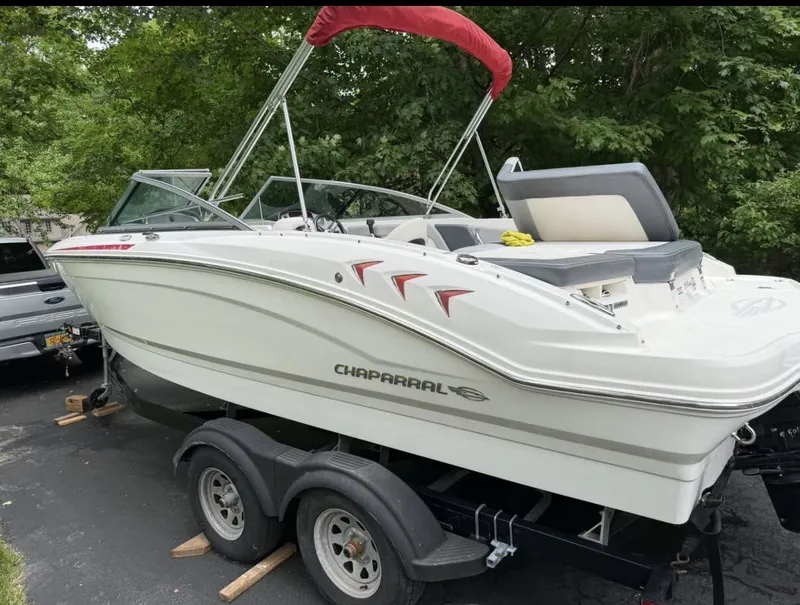 Slide: The Image of A 2020 Chaparral SSi 21 boat on a trailer, surrounded by trees. - 14