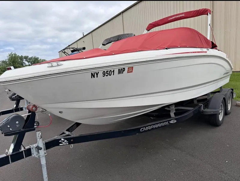 The Image of A white 2020 Chaparral SSi 21 boat with a red cover is on a trailer. - 1