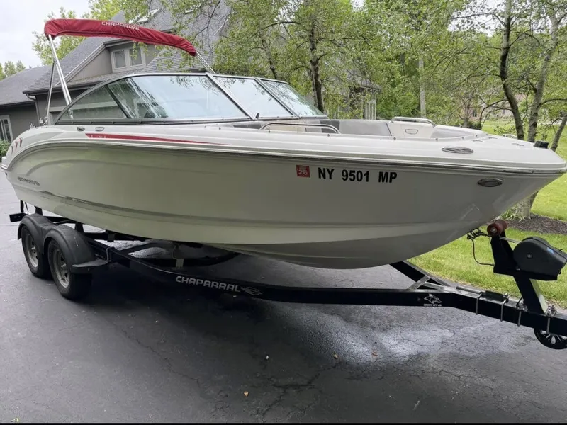 Slide: The Image of A 2020 Chaparral SSi 21 boat on a trailer, parked on a driveway in front of a house. - 6
