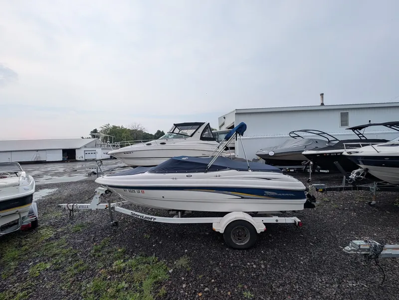Slide: The Image of A 2002 Chaparral 183 SSE boat on a trailer in a gravel lot, surrounded by other boats. - 6