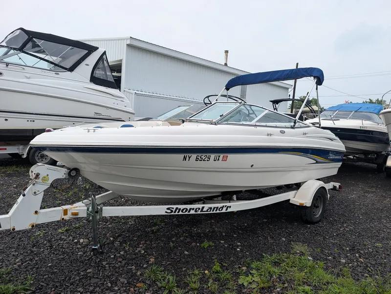 The Image of A white 2002 Chaparral 183 SSE boat on a trailer. It features a blue canopy. - 1