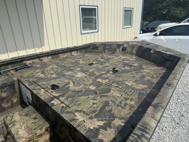 Slide: The Image of The image shows a Lowe Roughneck 1650SC boat with camouflage pattern, parked on a gravel lot. - 3