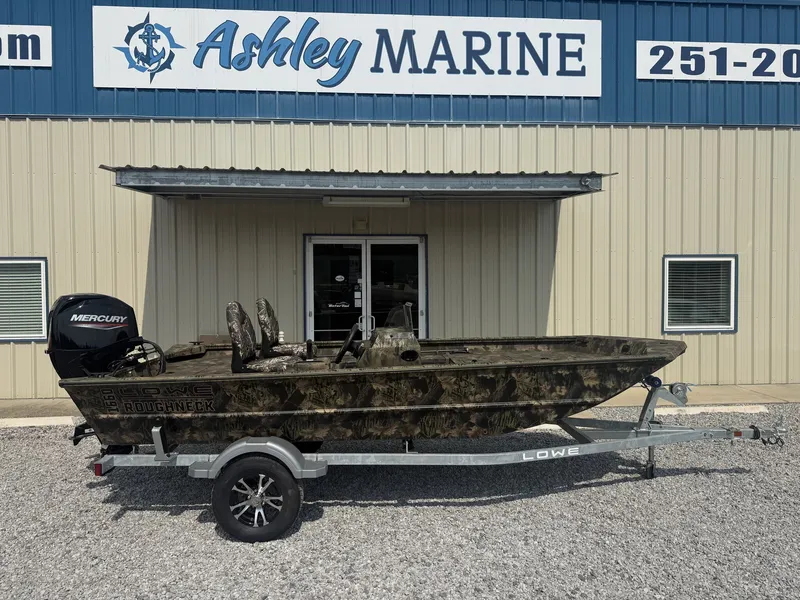 The Image of A 2027 Lowe Roughneck 1650SC boat on a trailer in front of a building with "Ashley Marine" signage. - 1