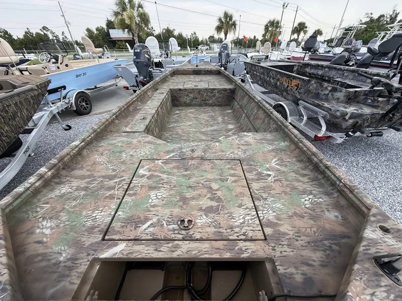 Slide: The Image of A rugged boat with camouflage pattern, surrounded by other boats on a gravel lot. - 9