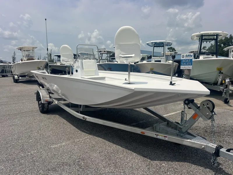 The Image of A white G3 Bay 18 boat on a trailer, surrounded by other boats in a parking lot. - 1
