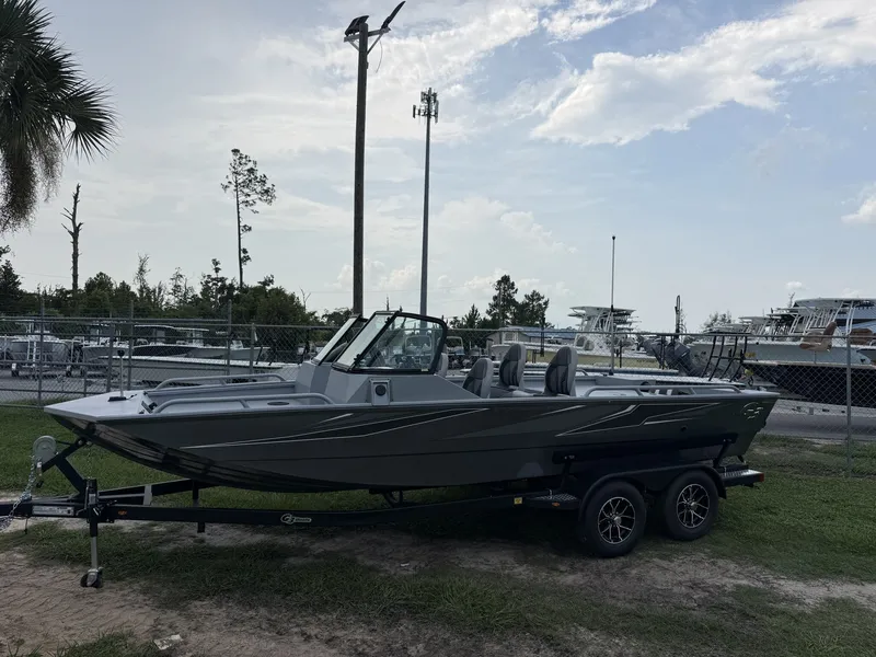 The Image of The image shows a gray G3 Sportsman 2100-CATFISH boat on a trailer, surrounded by trees and a fence. - 1