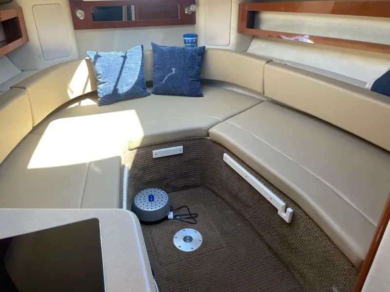Slide: The Image of Interior of a 2013 Sea Ray Sundancer 280 with beige upholstery and blue cushions. - 24