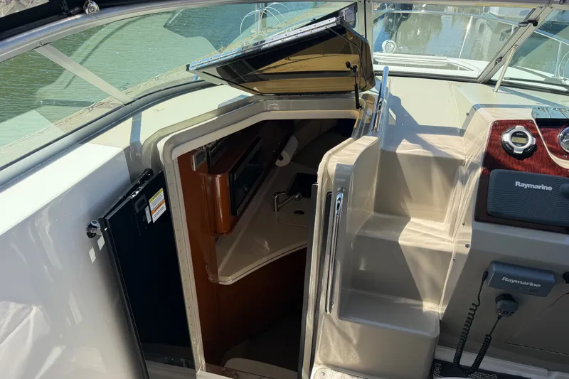 Slide: The Image of 2013 Sea Ray Sundancer 280 cabin entrance with Raymarine electronics, docked on calm water. - 21